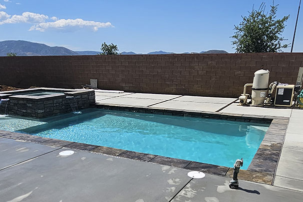 A serene pool area featuring a hot tub and a spacious patio