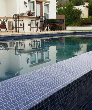 A serene pool featuring a vibrant blue mosaic tile design along its side