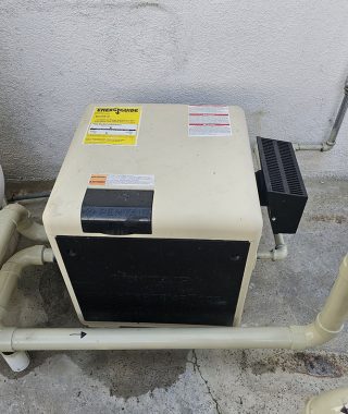 A compact water heater positioned on the ground adjacent to a wall