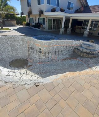 A man stands beside a pool undergoing repairs