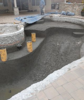 A construction site in a backyard featuring a pool under development