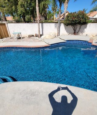 Individual with arms lifted stands before a shimmering pool