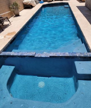 A serene pool featuring a blue tiled floor and matching blue tiled walls