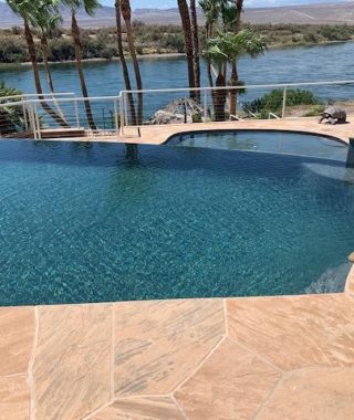 A serene pool overlooking a river, framed by majestic mountains in the background, creating a picturesque landscape.