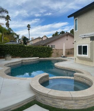 A serene backyard featuring a pool, surrounded by a patio and a stylish patio table for outdoor relaxation.