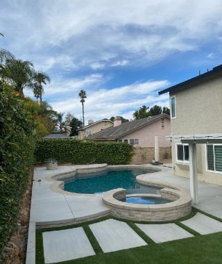 A serene backyard featuring a pool, surrounded by a patio and a stylish patio table for outdoor relaxation.