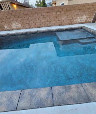 A serene pool featuring a sturdy concrete wall and a practical concrete step for easy access.