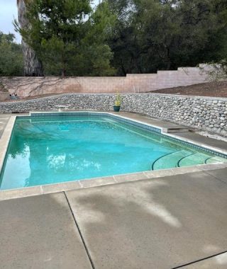 A serene backyard pool surrounded by a stone wall