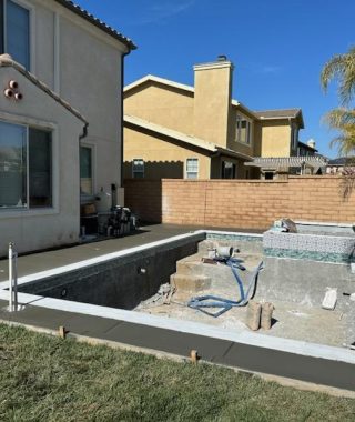 A construction site in a backyard featuring a pool under development