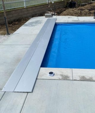 A pool covered with a blue tarp and a metal cover