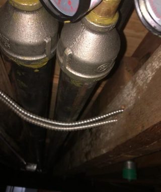 A pipe and valve installed in a dimly lit basement