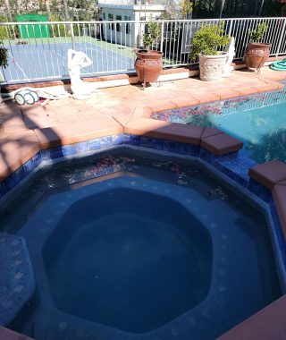 A backyard featuring a pool with a centrally located hot tub