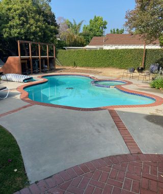 A serene pool surrounded by a brick patio, featuring a spacious outdoor area