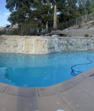 A serene pool surrounded by a stone wall and a natural rock wall