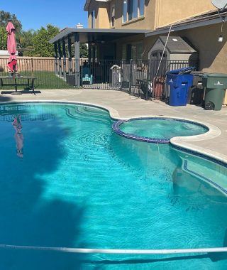 A serene backyard featuring a pool, a cozy patio, and a grill for outdoor cooking and relaxation.