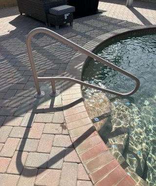 A handrail positioned at the edge of a pool, providing safety and support for individuals entering or exiting the water.