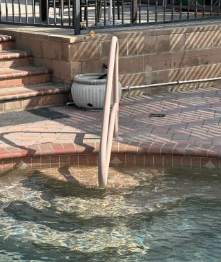 A handrail positioned at the edge of a pool, providing safety and support for individuals entering or exiting the water.