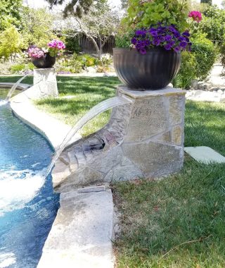 A serene pool featuring a cascading waterfall, surrounded by lush greenery, creating a tranquil outdoor oasis.