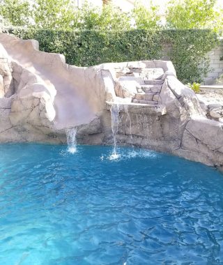 A serene pool featuring a cascading waterfall and a natural rock wall