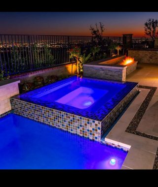 A serene pool illuminated by blue lights, surrounded by a softly lit area, creating a tranquil evening atmosphere.